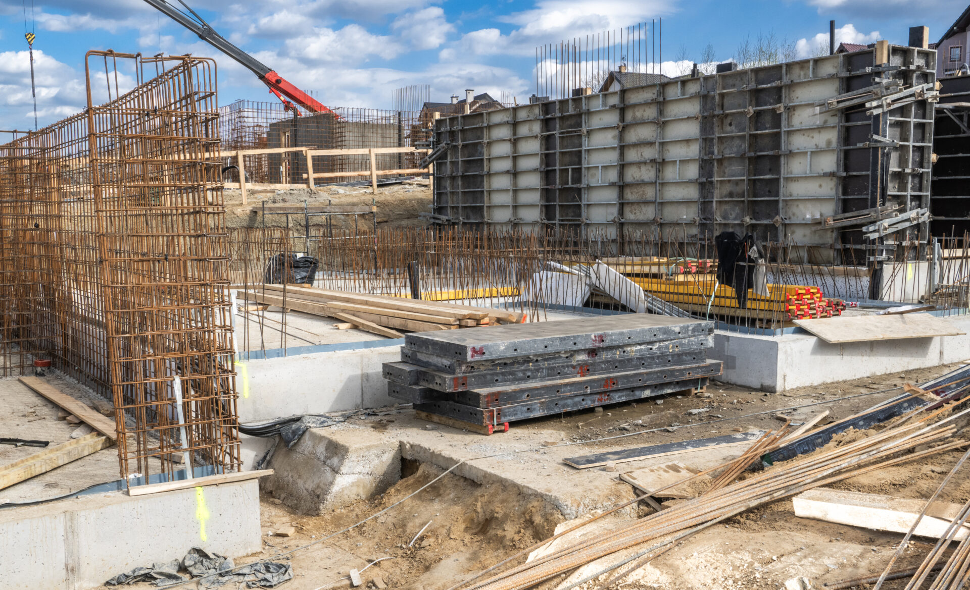 Construction Site With Foundation Work Underway in an Urban Area Surrounded by Machinery and Materials During a Clear Day