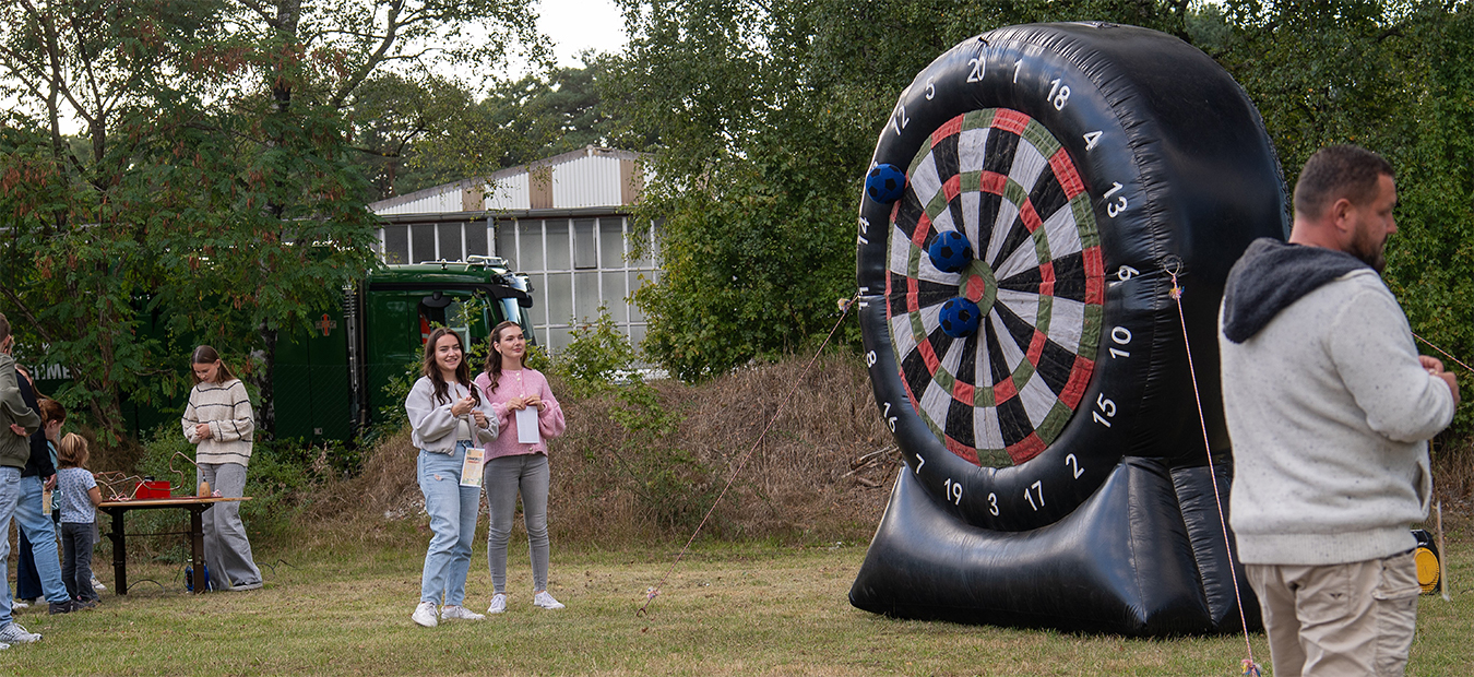 Gäste spielen an der Fußball-Darts-Wand; links der „Heiße Draht“, Zuschauer feuern an.