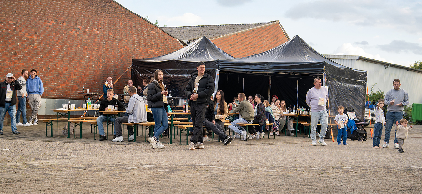 Sommerfest-Stimmung an Bierzeltgarnituren unter schwarzen Pavillons.