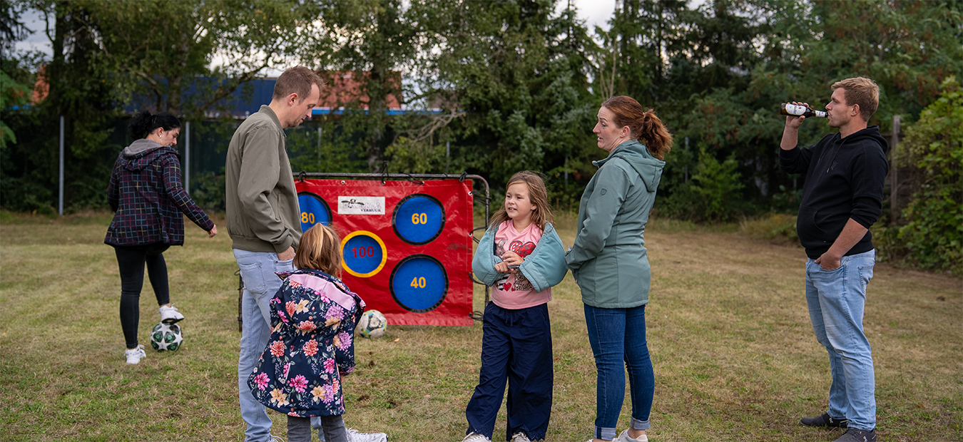Kinder und Eltern probieren die Torwand mit Punktzielen auf der Wiese.